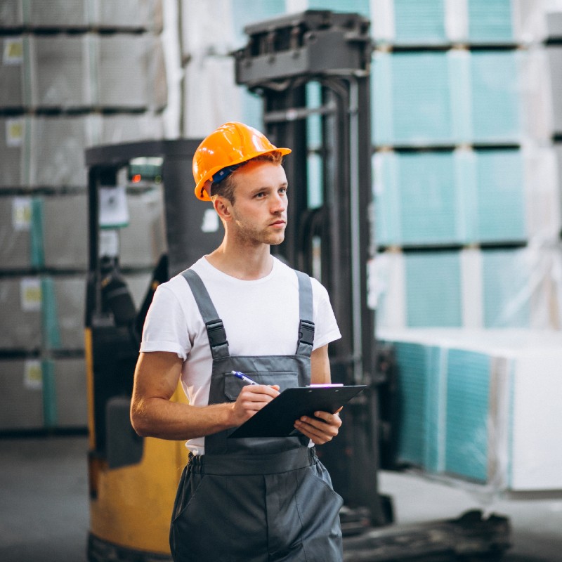 Un cariste dans un entrepôt porte un casque orange