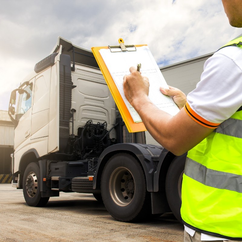 Un chauffeur PL prépare un document devant son camion